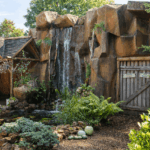 Tuinwaterval met rotsen, planten en een houten poort.