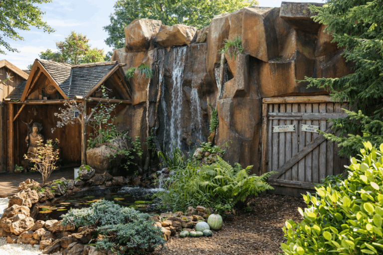 Tuinwaterval met rotsen, planten en een houten poort.
