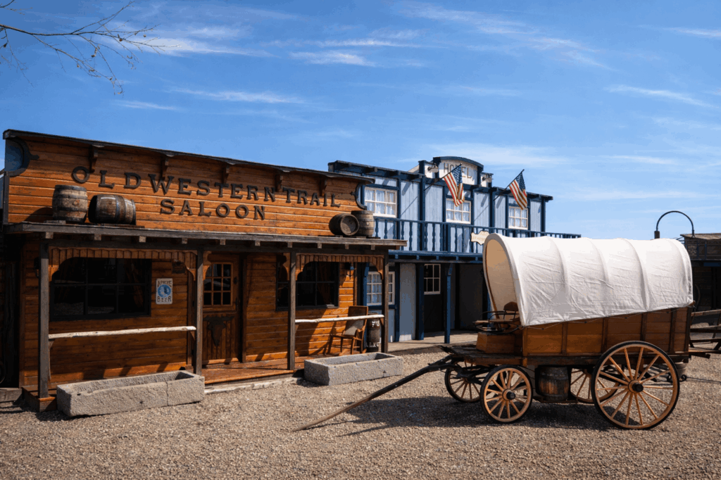 Oude westernstraat met een saloon, wagen en houten gevels.